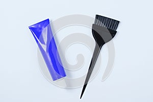 Blue tube hair dye and hair dye brush. White background