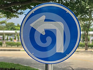 Blue turn left sign on pole