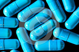 Blue turquoise capsule pills on a black background - drug, pharmaceutical