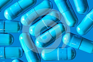 Blue turquoise capsule pills on a blue background - drug, pharmaceutical