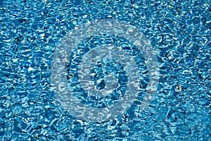 Blue and turquoise water. Blue colored pool pattern with bright and dark parts and sun reflections