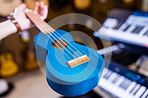 a blue ukulele in saler hand in musical shop