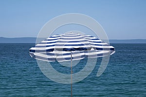 Blue umbrella on summer beach. Sea beach with sun umbrella waiting for tourists. Happy summer vacations and rest concept