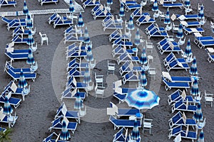 Blue umbrellas and chaise longue on empty sandy beach, Amalfi, Italy