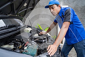 Blue uniform car engineer worker looking into car`s engine