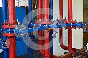The blue valve on the hot water pipeline is painted red. Industrial background.