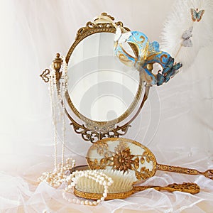 blue venetian mask next to old vintage oval mirror