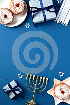 Blue vertical background with golden menorah, candles, sufganiyot , and gift boxes. Traditional Jewish holiday Hanukkah