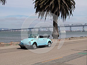 Blue VW convertible by bay