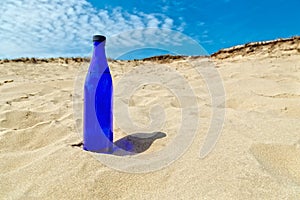 Blue water bottle standing in dry yellow sand