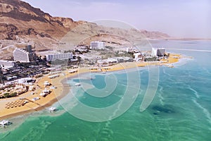 Blue water in the dead sea in the foreground on the background of the resort town of Ein Bokek in the middle of the desert in