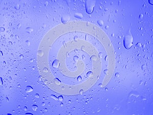 Blue water drops  on window glass of car, rain water background
