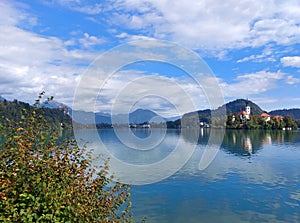 blue water of lake Bled and island with church under blue sky with white clouds. Slovenia