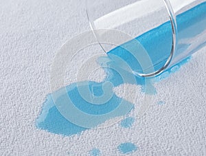a blue water pours from a glass onto a waterproof cloth.