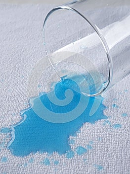 Blue water pours from a glass onto a waterproof cloth