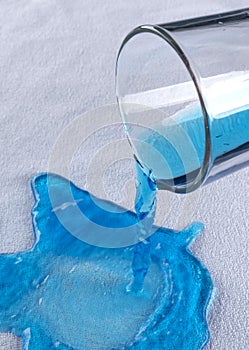 Blue water pours from a glass onto a waterproof cloth