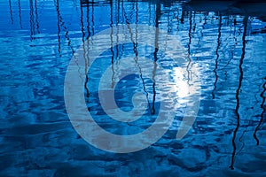 Blue water reflection of sailboats boats poles in waves