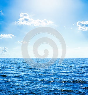 blue water in sea and sun with clouds in sky