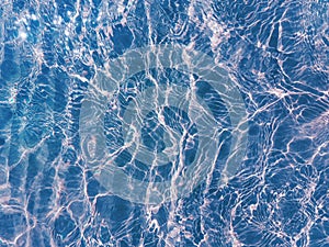 Blue water surface viewed from above in outdoor sea, sun reflection, dimply. Surface Abstract Background. Clear water in sea with