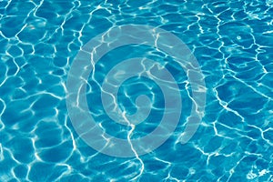 Blue water in swimming pool background. Ripple Water in swimming pool with sun reflection. Blue swimming pool rippled water detail