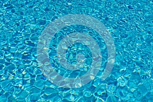 Blue water in swimming pool background. Ripple Water in swimming pool with sun reflection. Blue swimming pool rippled water detail