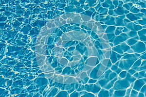 Blue water in swimming pool background. Ripple Water in swimming pool with sun reflection. Blue swimming pool rippled water detail