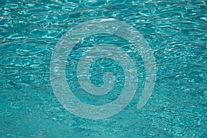 Blue water in swimming pool background. Ripple Water in swimming pool with sun reflection. Blue swimming pool rippled water detail