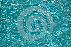 Blue water in swimming pool background. Ripple Water in swimming pool with sun reflection. Blue swimming pool rippled water detail