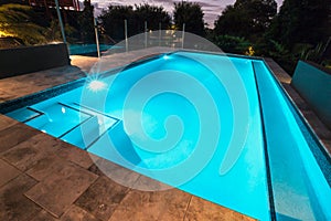 Blue water swimming pool with flashing lights with floor tiles