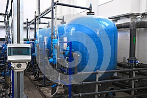 Blue water tanks inside wastewater treatment facility with sensors, industrial interior