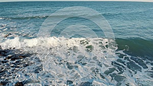 Blue water waves surface with white foam in sunny day, beautiful pattern background of nature with copy space. Colorful