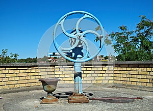 Blue water well pump, with wheel, on summer sun