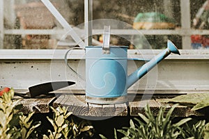 Blue watering can with trowel on wooden table