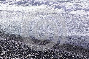 Blue wave surf on a pebble beach background