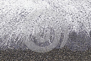 Blue wave surf on a pebble beach background