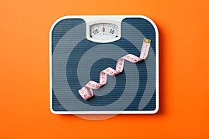 Blue weigh scales with measuring tape on orange background photo