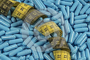 Blue weight loss pills and measuring tape symbolizing slimming