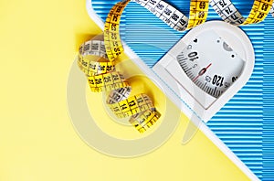 Blue weight scale and tape measure on yellow background. Sport equipment. Healthy lifestyle and diet concept. Yellow and light