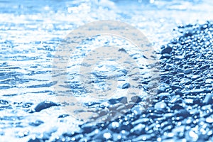 Blue wet pebble stones and water at morning seaside