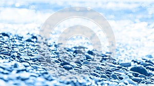 Blue wet pebble stones and water at morning seaside