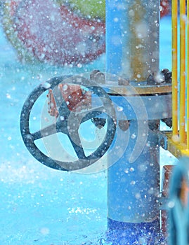 Blue wheel valve with pipe and wather flooding around