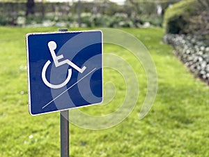 Blue wheelchair handicap sign against a green garden background
