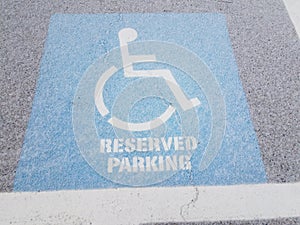 Blue wheelchair reserved parking sign on black asphalt with white snow