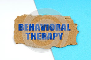 On a blue and white background lies a piece of cardboard with the inscription - Behavioral Therapy