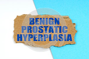 On a blue and white background lies a piece of cardboard with the inscription - Benign Prostatic Hyperplasia