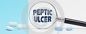 On a blue and white background, there are pills and a magnifying glass, inside of which it is written - Peptic ulcer