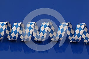 A blue and white bavarian paper streamer are lying on a blue ground