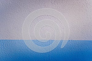 Blue and white bicolor background of a textured wall illuminated laterally by sunlight