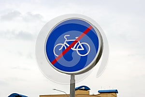 Blue and white bicycle lane sign with red forbid line indicating the end of the bike route, large round roadside traffic signage.