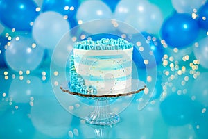 Blue and white birthday cake with balloons in the background